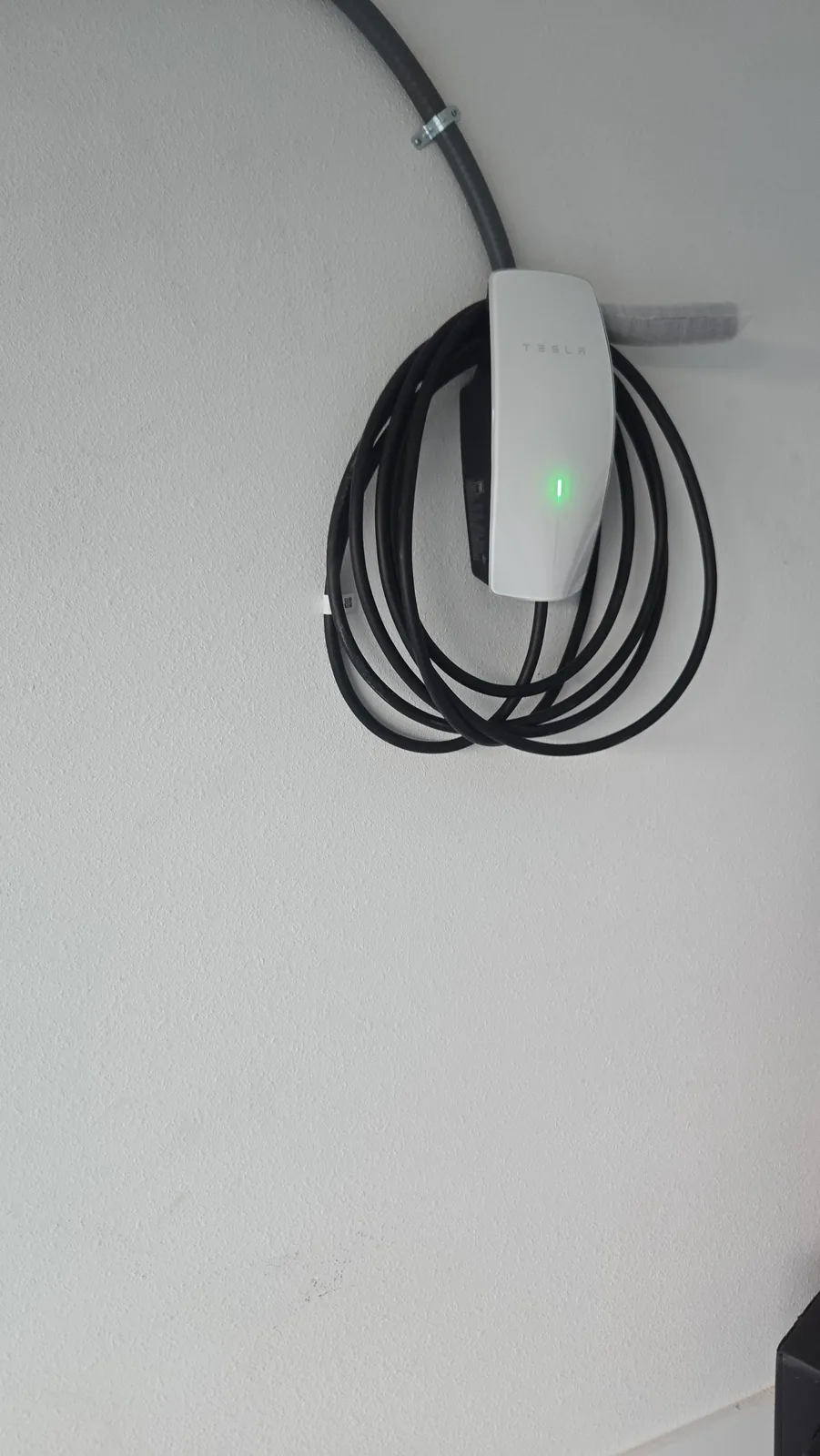 Wall-mounted electric vehicle charger with its cable neatly coiled