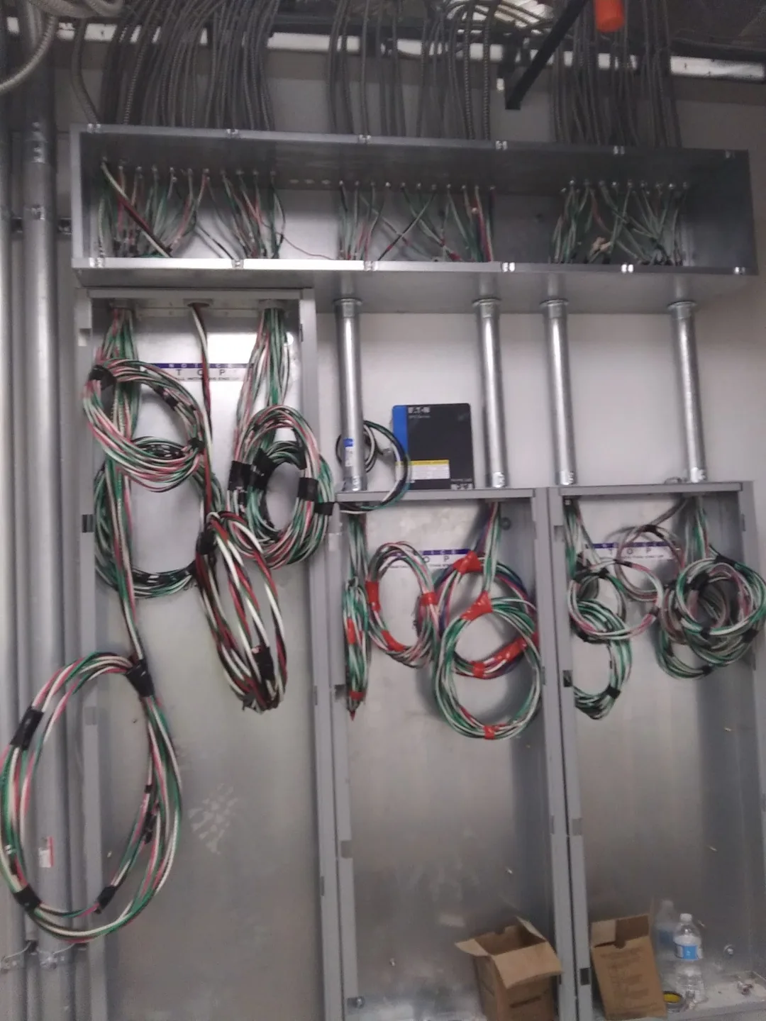 Commercial service wall with multiple electrical panels and coiled branch wiring